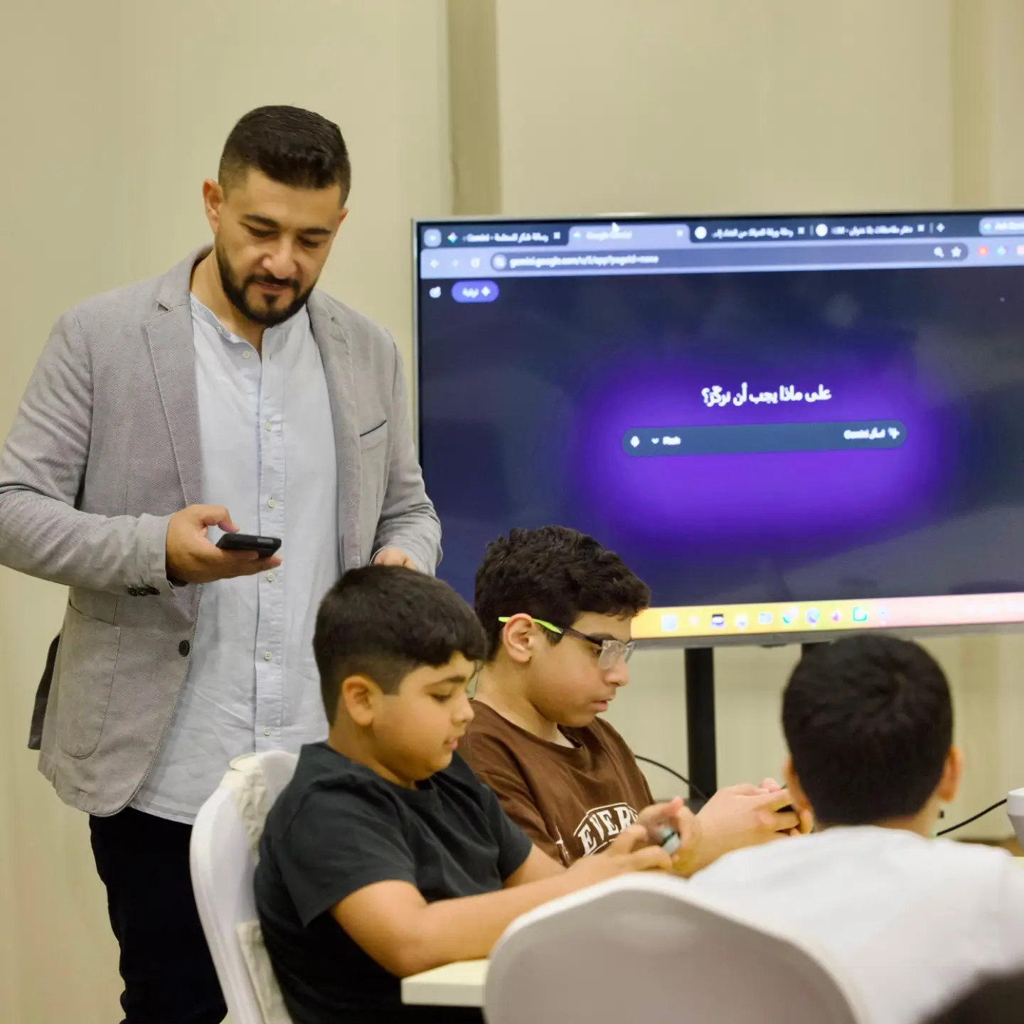 أحمد مهنا يشرح بجانب شاشة كبيرة عليها واجهة طلب بالعربية